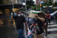 People take cover from the rain with pieces of cardboard in Caracas, Venezuela, Wednesday, June 29, 2022. As the latest tropical disturbance advances through the area, Venezuela shuttered schools, opened shelters and restricted air and water transportation as President Nicolas Maduro noted that the South American country already has been struggling with recent heavy rains. (AP Photo/Ariana Cubillos)