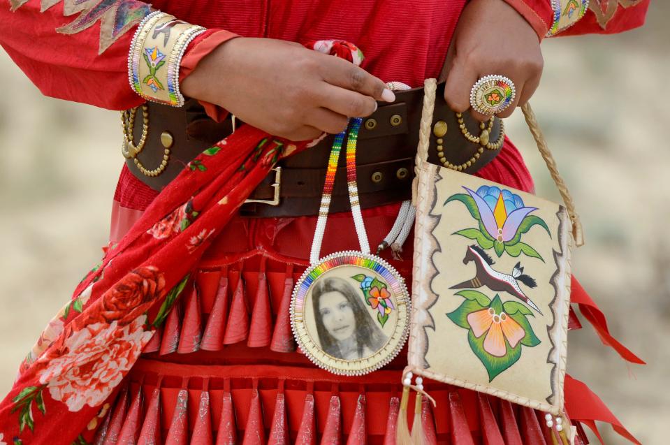 Ariel Price-Perry attaches a beaded medallion with a photo of her aunt Crystal Perry to her Native American regalia.