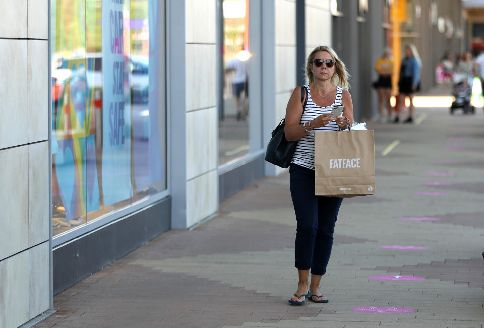 RUSHDEN, UNITED KINGDOM - JUNE 15:  A shopper carry goods bought at the Fat Face store at the Rushden Lakes shopping complex on June 15, 2020 in Rushden, United Kingdom. The British government have relaxed coronavirus lockdown laws significantly from Monday June 15, allowing zoos, safari parks and non-essential shops to open to visitors.  Places of worship will allow individual prayers and protective facemasks become mandatory on London Transport.  (Photo by David Rogers/Getty Images)