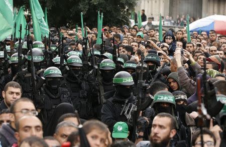 People watch as Palestinian members of al-Qassam Brigades, the armed wing of the Hamas movement, take part in a military parade marking the 27th anniversary of Hamas' founding, in Gaza City December 14, 2014. REUTERS/Mohammed Salem