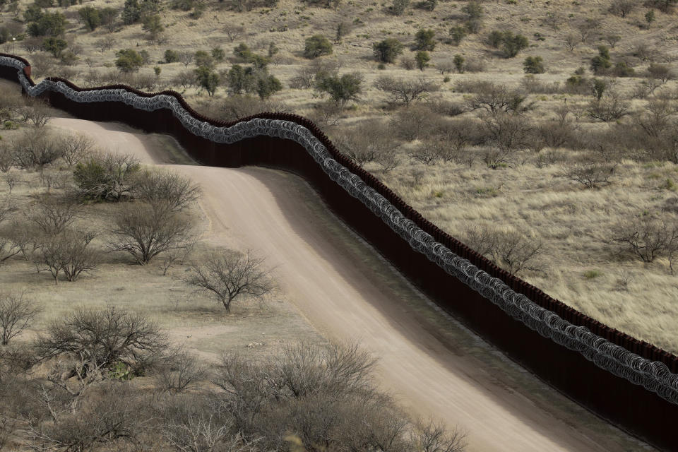 FILE - In this March 2, 2019 file photo, a razor-wire-covered border wall separates the United States, at left, from Mexico east of Nogales, Ariz. Activists, officials and social workers in Central America were staggered by the idea that U.S. President Donald Trump thinks he will help reduce immigration by cutting off nearly $500 million in aid to Honduras, Guatemala and El Salvador; exactly the opposite will happen, they say. (AP Photo/Charlie Riedel, File)