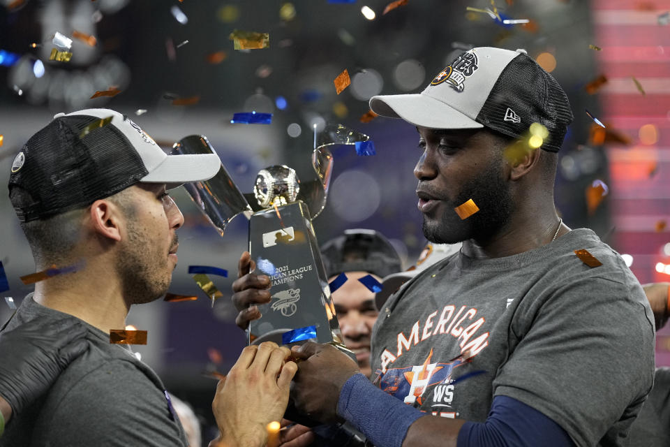 Houston Astros designated hitter Yordan Alvarez and shortstop Carlos Correa hold the trophy after their win against the Boston Red Sox in Game 6 of baseball's American League Championship Series Friday, Oct. 22, 2021, in Houston. The Astros won 5-0, to win the ALCS series in game six. (AP Photo/David J. Phillip)