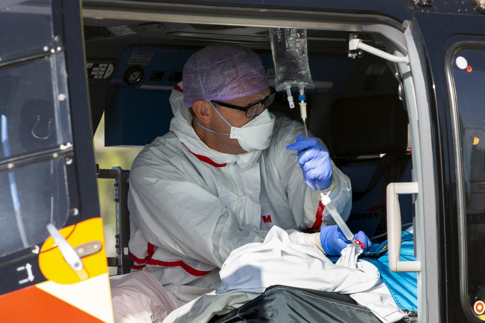 A COVID-19 patient is being tended to prior to being airlifted with a helicopter from Flevoziekenhuis, or FlevoHospital, in Almere, Netherlands, Friday, Oct. 23, 2020. In the latest sign of the scale of the coronavirus pandemic sweeping across Europe, a helicopter started airlifting COVID-19 patients from the Netherlands to an intensive care unit in the German city of Muenster.(AP Photo/Peter Dejong)