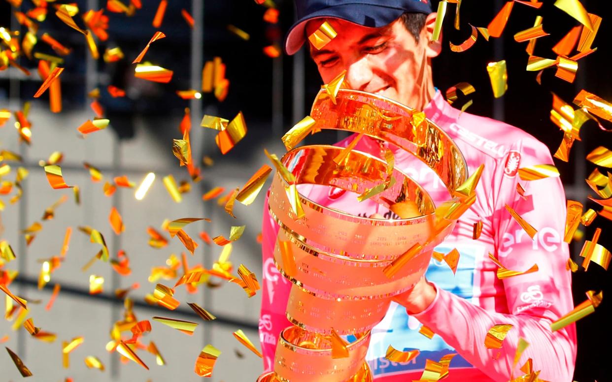 Richard Carapaz, dressed in the pink jersey of the Giro d'Italia winner, celebrates on the podium after receiving the Trofeo Senza Fine on becoming the first Ecuadorian to win the three-week race - AFP or licensors