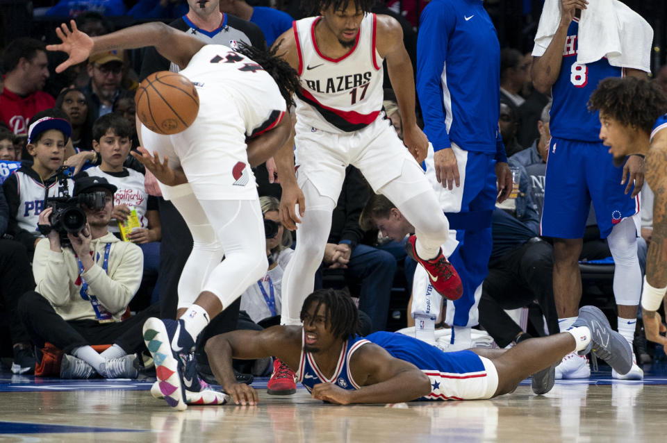 Philadelphia 76ers' Tyrese Maxey, bottom, watches as Portland Trail Blazers' Jabari Walker, left, throws the ball between his legs during the first half of an NBA basketball game, Sunday, Oct. 29, 2023, in Philadelphia. (AP Photo/Chris Szagola)