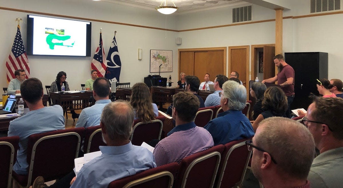 Granville Village Council and residents listen to Adam Himes, the chair of the Munson Springs Steering Committee, share the group's development recommendations for a 57-acre site along Newark-Granville Road during the July 19 village council meeting.