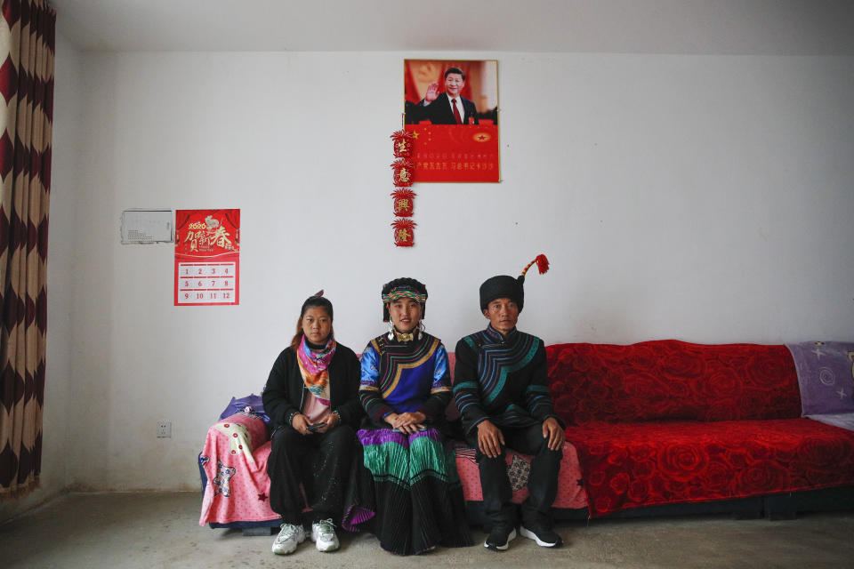 A minority Yi family sits inside their home displaying a poster of Chinese President Xi Jinping in Xujiashan village in Ganluo County, southwest China's Sichuan province on Sept. 10, 2020. Communist Party Xi’s smiling visage looks down from the walls of virtually every home inhabited by members of the Yi minority group in a remote corner of China’s Sichuan province. Xi has replaced former leader Mao Zedong for pride of place in new brick and concrete homes built to replace crumbling traditional structures in Sichuan’s Liangshan Yi Autonomous Prefecture, which his home to about 2 million members of the group. (AP Photo/Andy Wong)