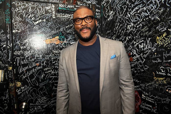 Tyler smiles for a photo in front of a wall filled with people's signatures