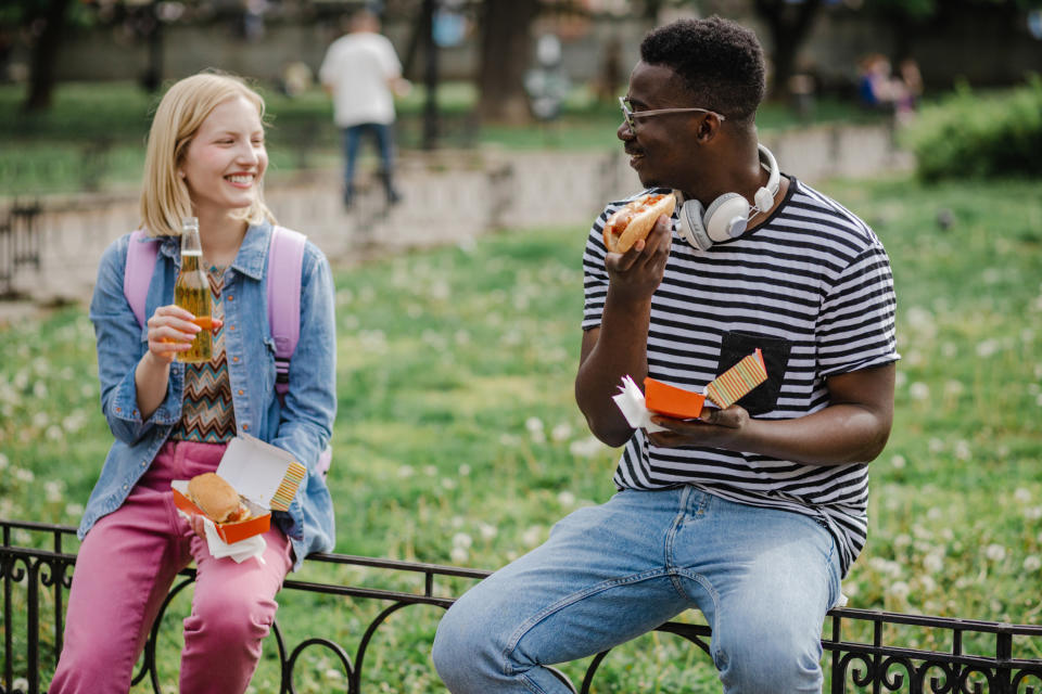 Couple eating hot dogs in the park