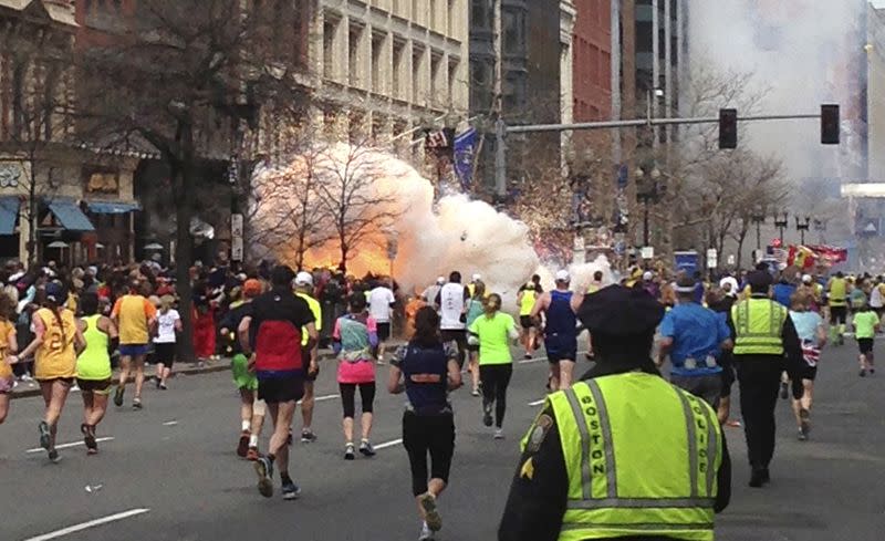 FILE PHOTO: File photo of runners continue to run towards the finish line as an explosion erupts at the finish line of the Boston Marathon