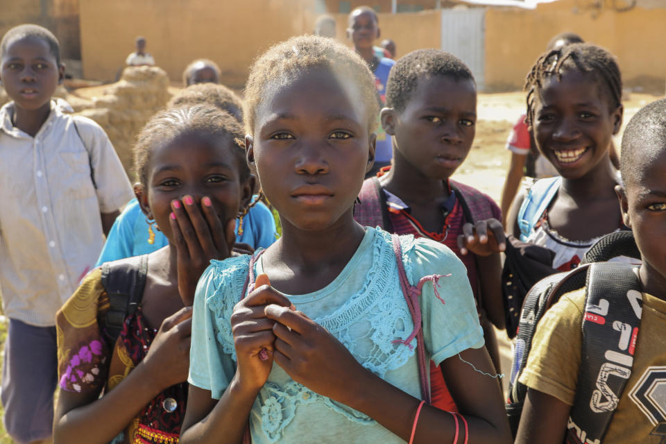 FILE- Balkissa Barro, 10, center, walks to school with friends in the Burkina Faso village of Dori Tuesday Oct. 20, 2020. More than half of the displaced by growing violence between Islamic extremists and security forces are children, and many are traumatized by their experiences. But mental health services in the West African country are limited, and children are often overlooked for treatment.(AP Photo/Sam Mednick, File)