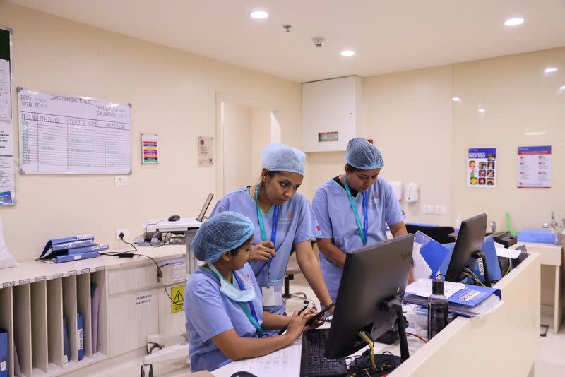 FILE PHOTO: Healthcare workers check computer screens at a hospital in New Delhi