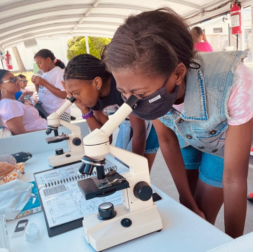 Two students eye newly collected plankton through a microscope as part of a marine education field trip on a Florida Water Warriors vessel.