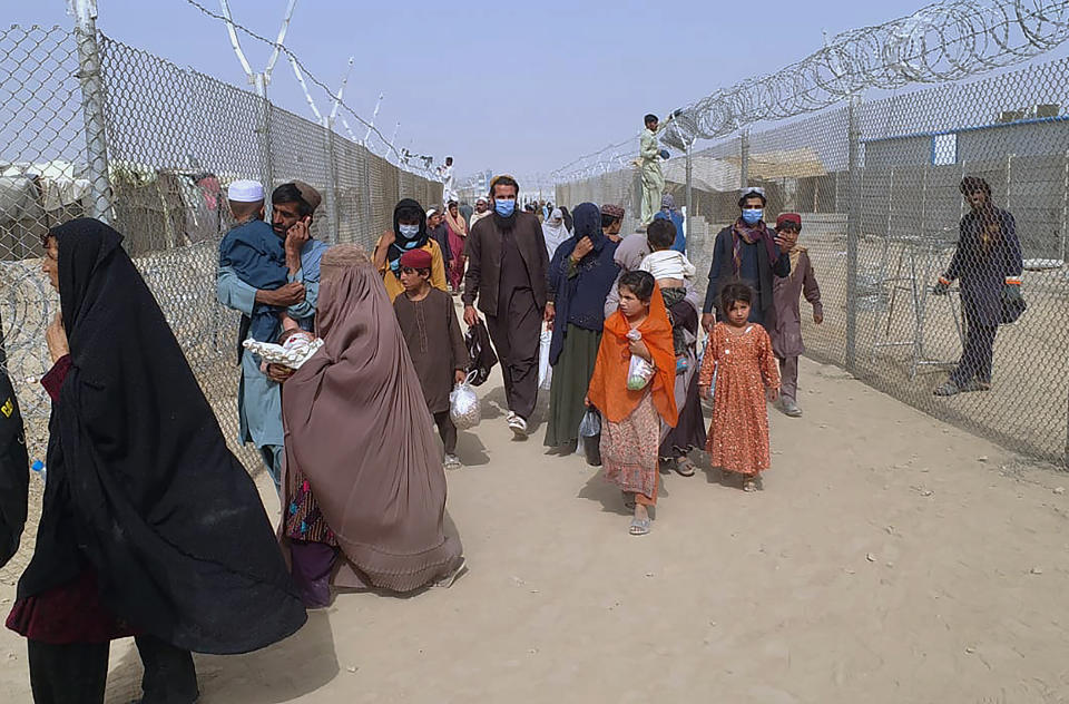 Travelers enter in Pakistan through a border crossing point in Chaman, Pakistan, Monday, Aug. 16, 2021. A special flight of Pakistan’s national airline PIA has arrived in Islamabad carrying 329 passengers from Kabul, and another carrying 170 people will arrive later today. A spokesman for the airline said Saturday that the airline will operate three flights tomorrow to transport Pakistanis and other nationalities looking to leave Kabul. (AP Photo/Jafar Khan)