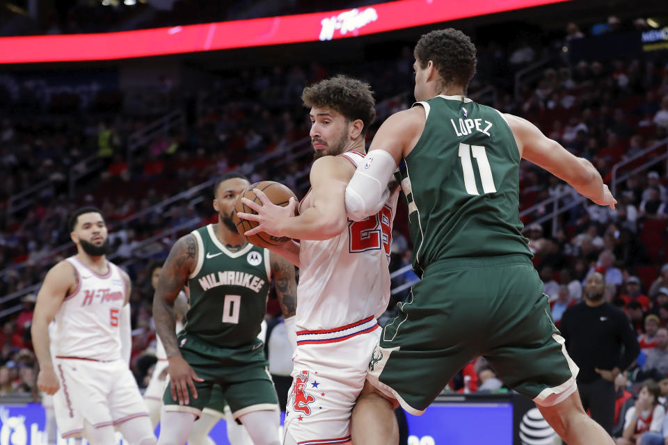 Houston Rockets center Alperen Sengun, second from right, spins to the basket between Milwaukee Bucks guard Damian Lillard (0) and center Brook Lopez (11) during the first half of an NBA basketball game Saturday, Jan. 6, 2024, in Houston. (AP Photo/Michael Wyke)