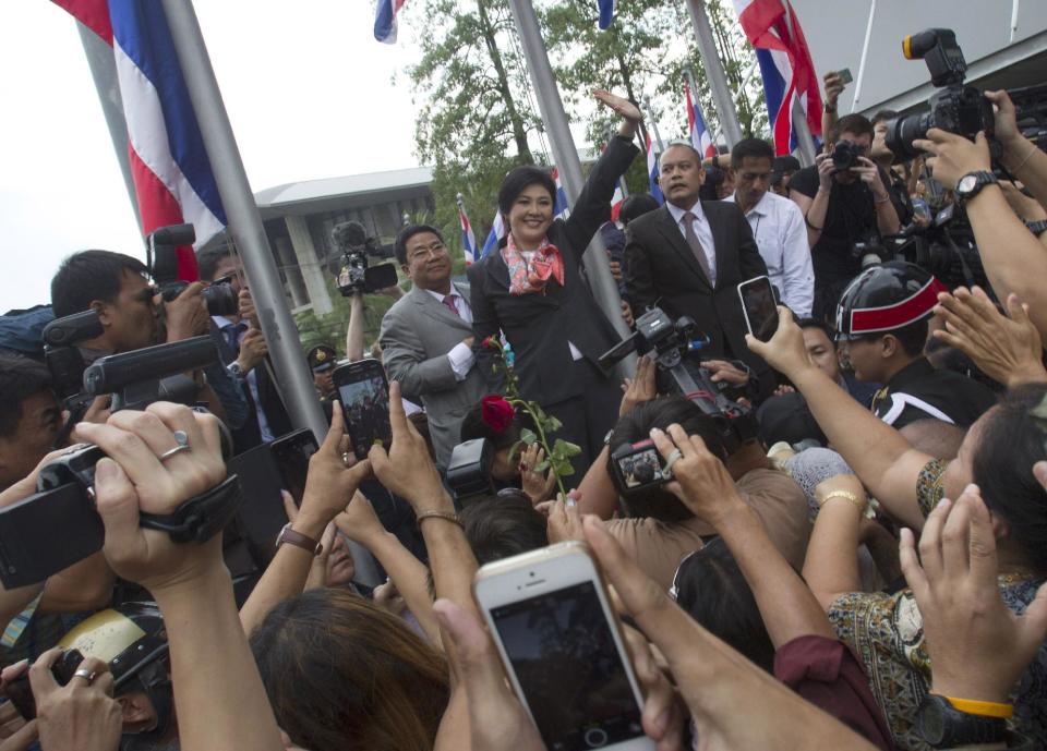 FILE - In this Wednesday, May 7, 2014 file photo, oustsed Thai Prime Minister Yingluck Shinawatra, center, waves to her supporters in Bangkok, Thailand shortly after she was ordered to step down by the Constitution Court ruling, finding her guilty in an abuse of power case. Thailand's anti-graft commission indicted ousted Yingluck on Thursday on charges of dereliction of duty in overseeing a widely criticized rice subsidy program, a day after the court forced her from office. (AP Photo/Sakchai Lalit, File)