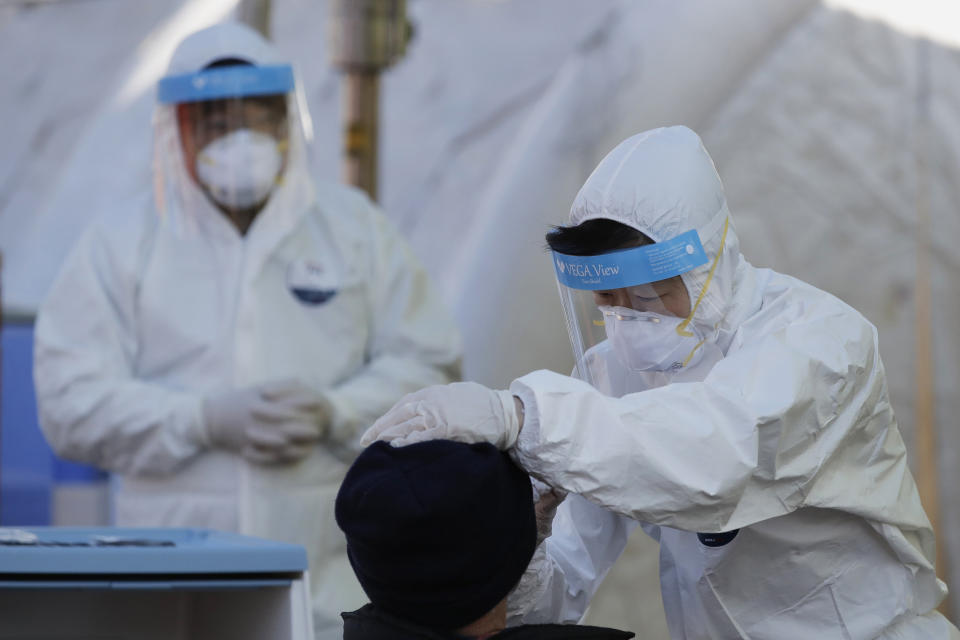 A medical worker wearing protective gear takes a sample from a man at a coronavirus/COVID-19 testing site in Seoul, South Korea, Sunday, Dec. 20, 2020. (AP Photo/Lee Jin-man)