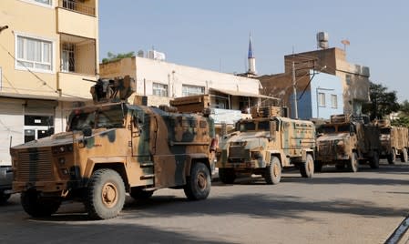 Turkish military vehicles drive to cross into Syria in the Turkish border town of Ceylanpinar