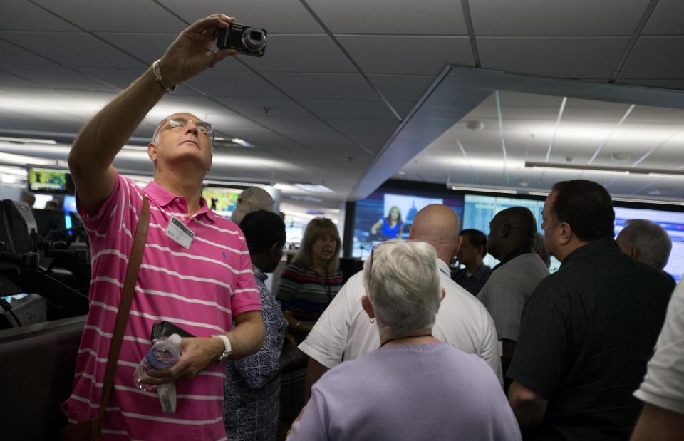 In this Friday, Sept. 20, 2013 photo, airport chaplain Rev. Canon Jonathan Baldwin, left, of London's Luton Airport, takes a photo while touring Delta Air Lines' Operations Customer Center while attending the International Association of Civil Aviation Chaplains' annual conference at the airline's headquarters, in Atlanta. Airports are mini-cities with their own movie theaters, fire departments and shopping malls. Many also have chapels, which are staffed by a mix of 350 part- and full-time chaplains worldwide who are Catholic, Protestant and, to a lesser extent, Jewish, Muslim or Sikh. (AP Photo/David Goldman)