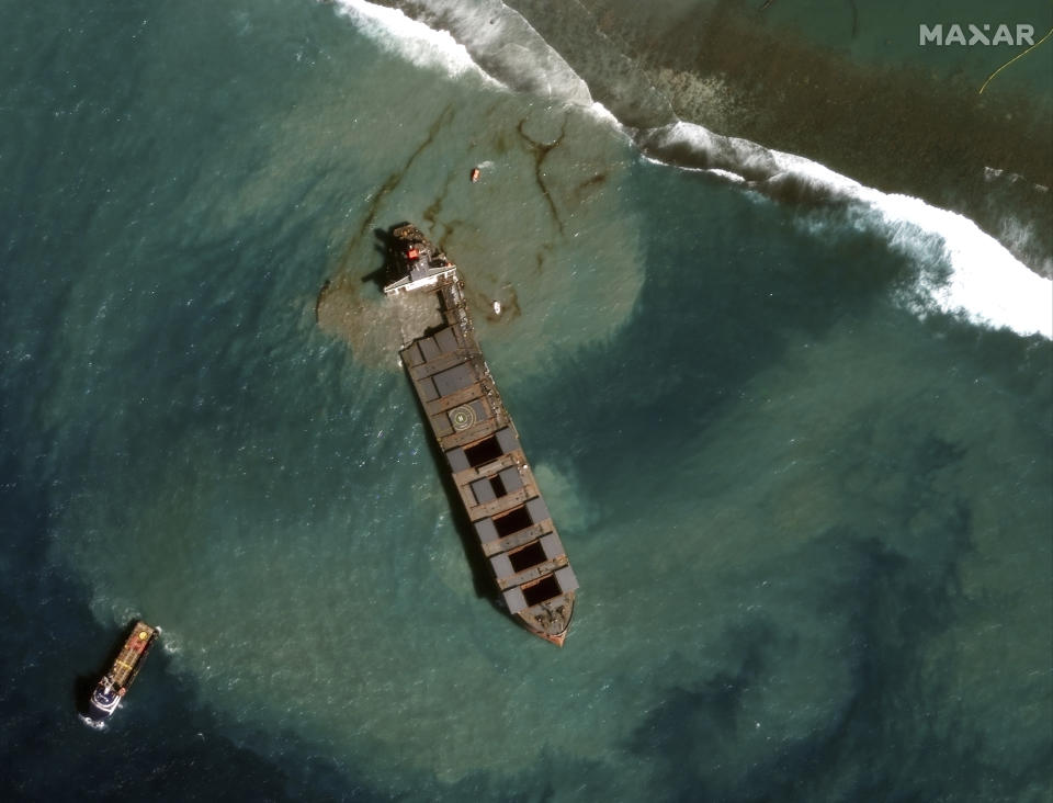 This satellite image provided by 2020 Maxar Technologies on Tuesday Aug. 18, 2020, showing an aerial view of the MV Wakashio, a bulk carrier ship that recently ran aground off the southeast coast of Mauritius. Officials say the grounded Japanese ship that leaked tons of oil near protected areas off the Indian Ocean island nation of Mauritius, has split apart with remaining fuel seen spreading into the turquoise waters. (2020 Maxar Technologies via AP)