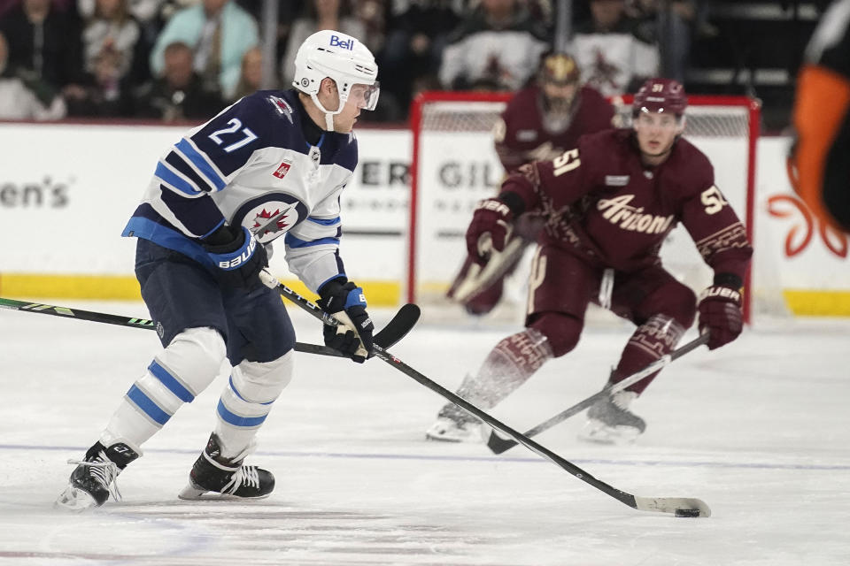Winnipeg Jets' Nikolaj Ehlers (27) controls the puck in front of Arizona Coyotes' Troy Stecher (51) during the first period of an NHL hockey game Sunday, Jan. 7, 2024, in Tempe, Ariz. (AP Photo/Darryl Webb)
