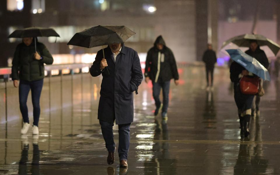 Commuters attempt to shelter as they cross London Bridge