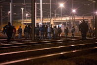 Police officers (L and R) push back migrants walking on the railway tracks of the freight shuttle leading to the entrance of the Channel Tunnel in Calais, France, October 14, 2015. REUTERS/Philippe Wojazer