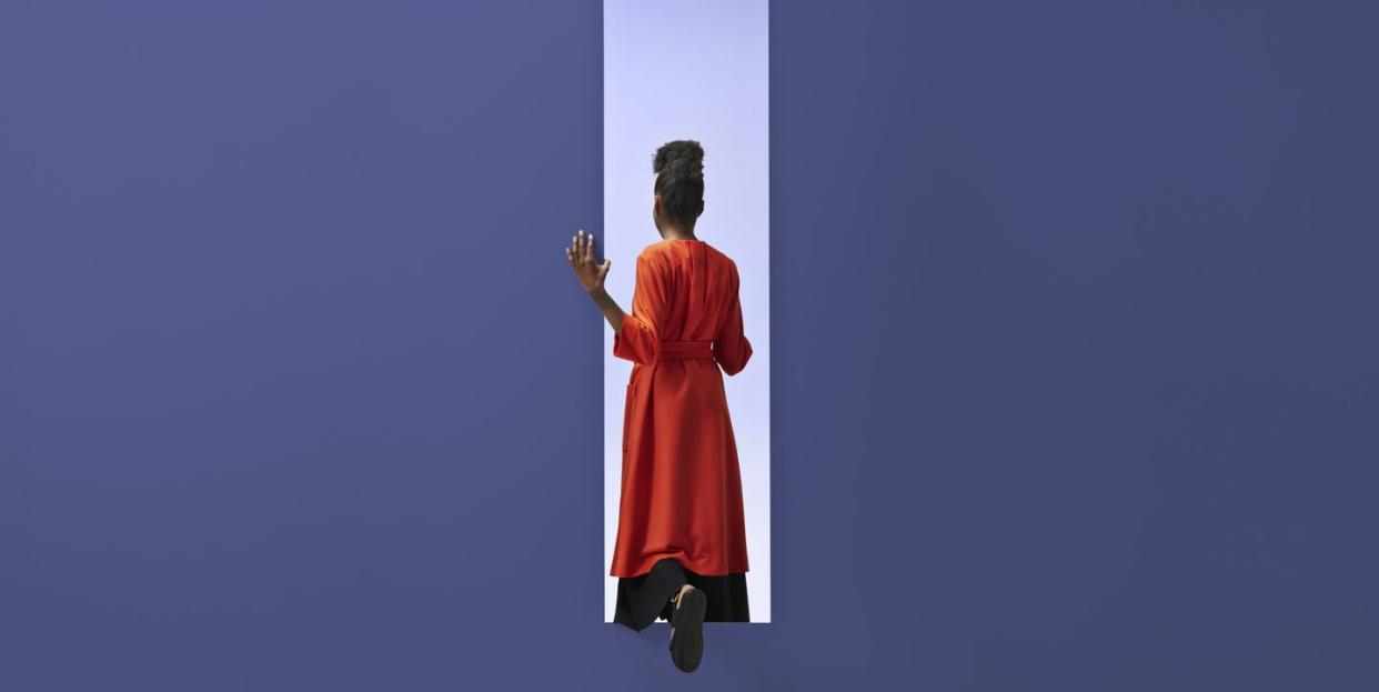 woman walking into rectangular opening in coloured wall