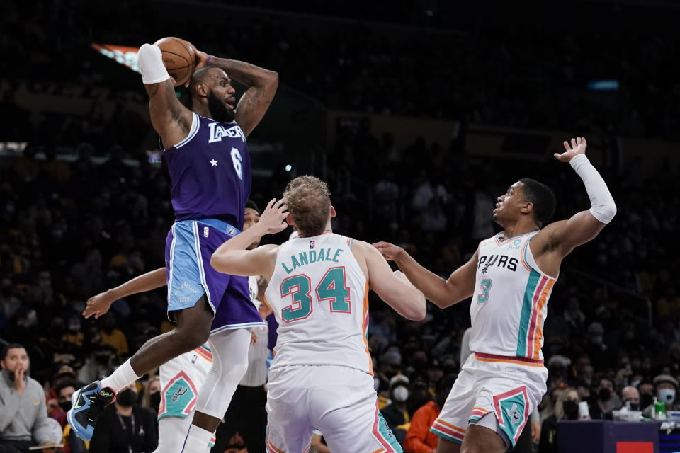 Los Angeles Lakers' LeBron James, top left, looks to pass under pressure by San Antonio Spurs' Jock Landale, center, and Keldon Johnson during first half of an NBA basketball game Thursday, Dec. 23, 2021, in Los Angeles. (AP Photo/Jae C. Hong)