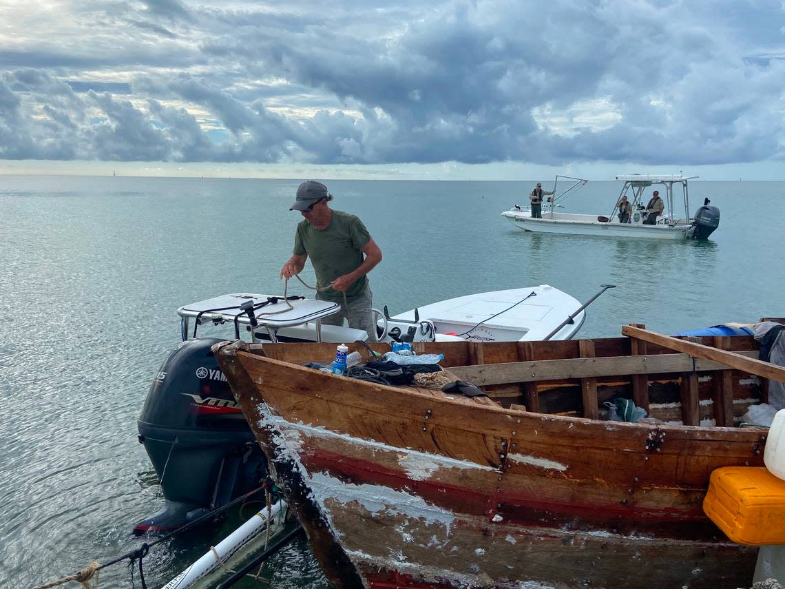 Florida Keys fishing guide Mark Cockerham ties a tow rope from a Cuban boat to his vessel Friday, Oct. 14, 2022, on Indian Key. Since the Keys has seen a marked increase of migrants in vessels littering the coast, Cockerham said he has been towing them to be preserved.