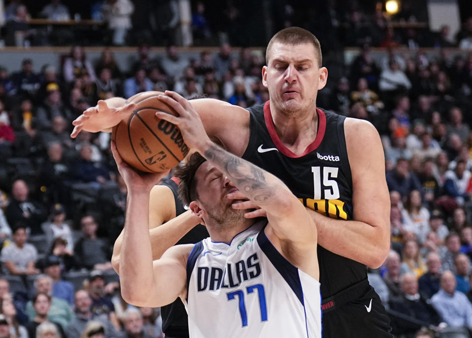 Denver Nuggets center Nikola Jokic (15) fouls Dallas Mavericks guard Luka Doncic (77) during the first quarter of an NBA basketball game Monday, Dec. 18, 2023, in Denver. (AP Photo/Jack Dempsey)