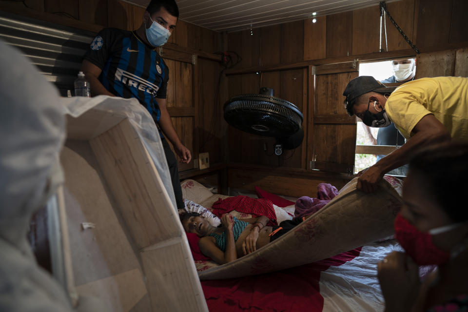 Los hijos de Leivane Bibiano, de 42 años, ayudan a un trabajador de SOS Funeral a retirar el cuerpo de su madre durante a pandemia del coronavirus, en Manaos, Brasil, el 12 de mayo de 2020. Según la familia de Bibiano, tenía problemas médicos previos y murió en su casa tras dos semanas con fiebre y tos. (AP Foto/Felipe Dana)