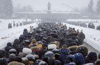 People walk in snowfall to the Motherland monument to place flowers at the Piskaryovskoye Cemetery where most of the Leningrad Siege victims were buried during World War II, in St.Petersburg, Russia, Saturday, Jan. 26, 2019. People gathered to mark the 75th anniversary of the battle that lifted the Siege of Leningrad. The Nazi German and Finnish siege and blockade of Leningrad, now known as St. Petersburg, was broken on Jan. 18, 1943 but finally lifted Jan. 27, 1944. More than 1 million people died mainly from starvation during the 900-day siege. (AP Photo/Dmitri Lovetsky)
