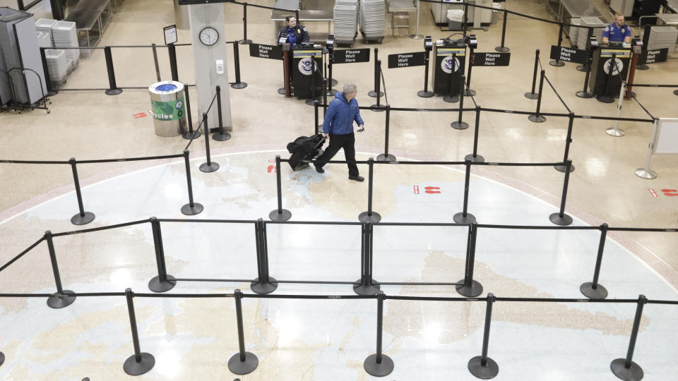 A traveler walks through the security line at the Salt Lake City International Airport Wednesday, March 25, 2020, in Salt Lake City. For the millions of Americans living under some form of lockdown to curb the spread of the new coronavirus, not knowing when the restrictions will end is a major source of anxiety. (AP Photo/Rick Bowmer)