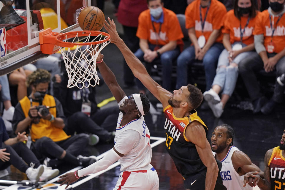 Utah Jazz center Rudy Gobert, center, defends against Los Angeles Clippers guard Reggie Jackson, left, during the first half of Game 2 of a second-round NBA basketball playoff series Thursday, June 10, 2021, in Salt Lake City. (AP Photo/Rick Bowmer)