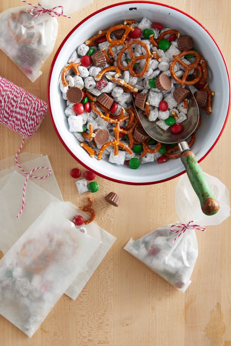 a sweet snack mix in a bowl with glassine bags filled with the mix laying on the table nearby