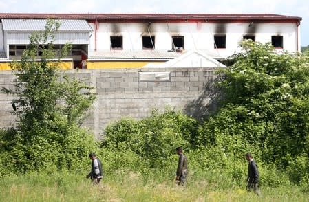 Migrants walk past a burned camp in Velika Kladusa