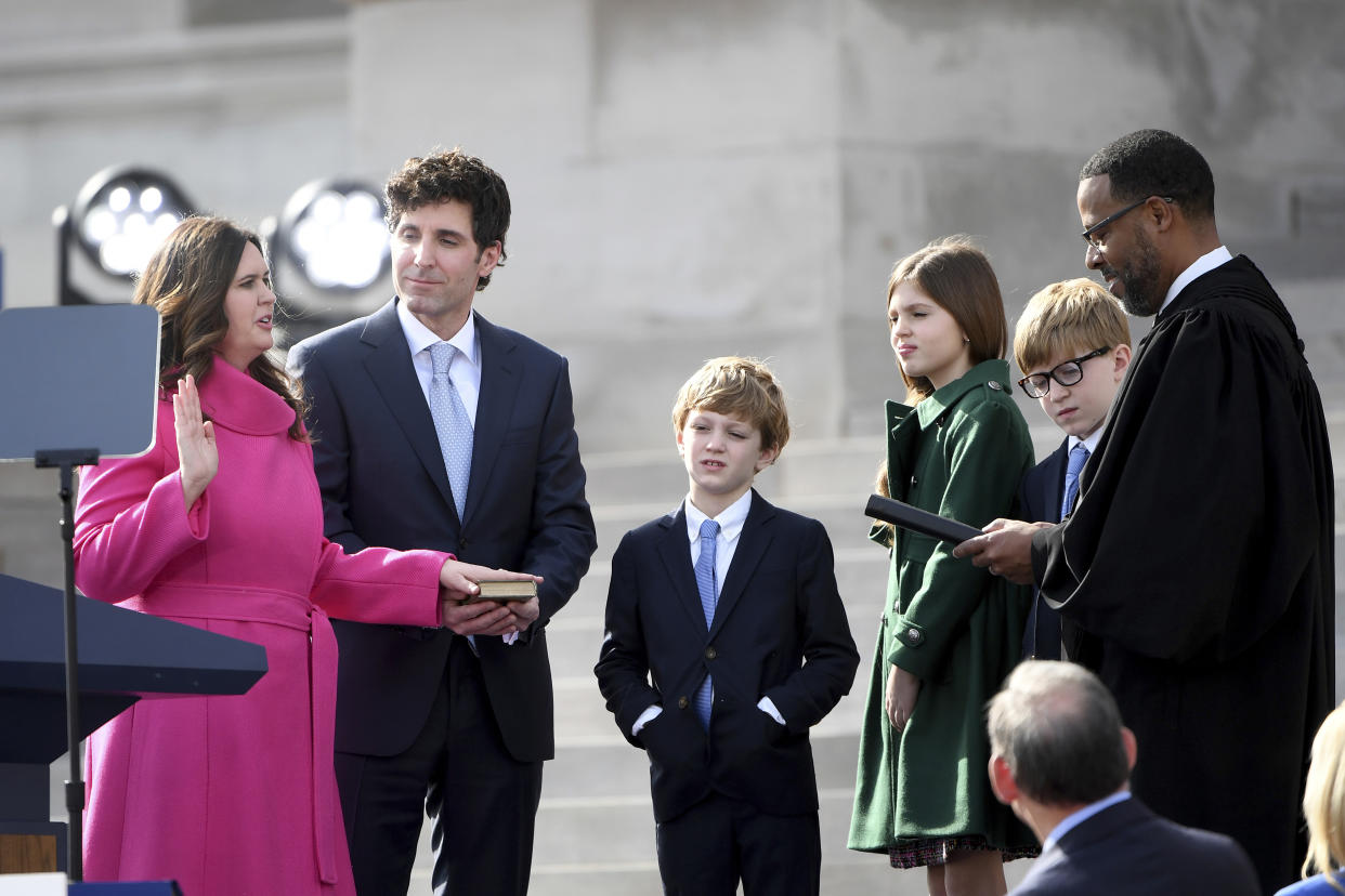 Arkansas Gov.-elect Sarah Huckabee Sanders takes the oath of the office administered by 8th Circuit Court judge Brian Miller on the steps of the Arkansas Capitol with husband Bryan and children Huck, Scarlett and George, Tuesday, Jan. 10, 2023, in Little Rock, Ark. (AP Photo/Will Newton)