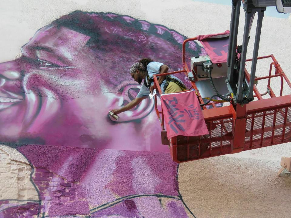 In this Thursday, May 30, 2019 photo, Brandon "BMike" Odoms shades in a detail of a mural in New Orleans. The mural is one of five created as part of an Arts Council of New Orleans project called "Unframed." (AP Photo/ Janet McConnaughey)