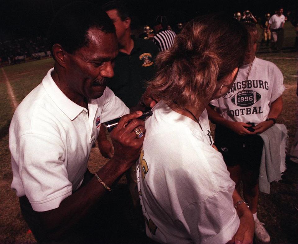 NFL Hall of Famer and former San Francisco 49ers star Jimmy Johnson signs a fan’s T-shirt following a 1996 jersey retirement ceremony at Kingsburg High in his honor. Johnson died Wednesday at age 86.