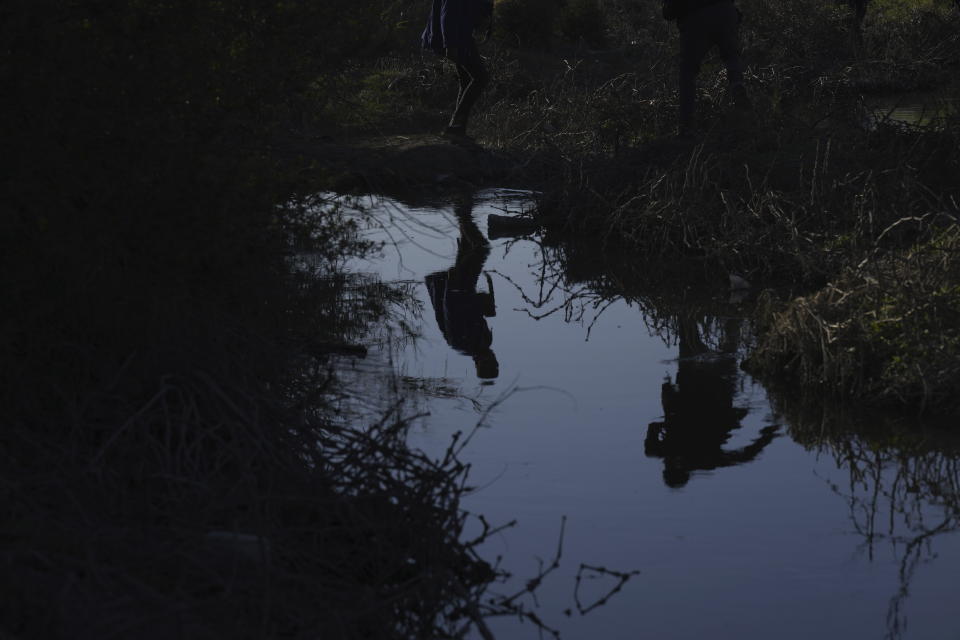 Migrants are seen reflected on the water as they jump over the Rio Grande river into the United States, from Ciudad Juarez, Mexico, Wednesday, March 29, 2023, a day after dozens of migrants died in a fire at a migrant detention center in Ciudad Juarez. (AP Photo/Fernando Llano)