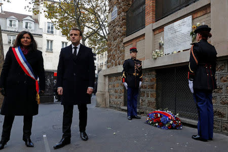 French President Emmanuel Macron (2ndL) and Paris Mayor Anne Hidalgo lay a wreath of flowers in front of a commemorative plaque next to "La Belle Equipe" bar and restaurant in Paris, France, November 13, 2017, during a ceremony held for the victims of the Paris attacks which targeted the Bataclan concert hall as well as a series of bars and killed 130 people. REUTERS/Philippe Wojazer