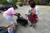 Amonda Washington, left, with Houston Independent School District Nutrition Services, places food in a cart for Wanda Williams Monday, April 6, 2020, in Houston. HISD relaunched their food distribution efforts throughout the district Monday, with a streamlined process that will implement increased safety measures. (AP Photo/David J. Phillip)