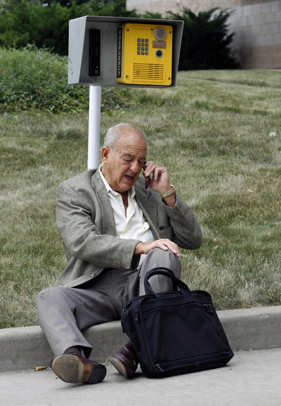 FILE - Dr. Cyril Wecht makes a phone call while sitting on a curb outside the facility he uses to perform autopsies, July 16, 2009, in Pittsburgh. Wecht, a pathologist and attorney whose biting cynicism and controversial positions on high-profile deaths such as President John F. Kennedy’s 1963 assassination caught the attention of prosecutors and TV viewers alike, died Monday, May 13, 2024. He was 93. (AP Photo/Keith Srakocic, File)