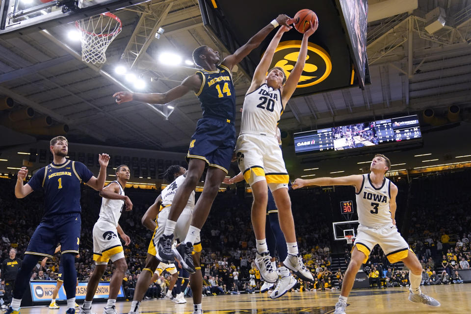 Michigan forward Moussa Diabate (14) fights for a rebound with Iowa guard Payton Sandfort (20) during the first half of an NCAA college basketball game, Thursday, Feb. 17, 2022, in Iowa City, Iowa. (AP Photo/Charlie Neibergall)