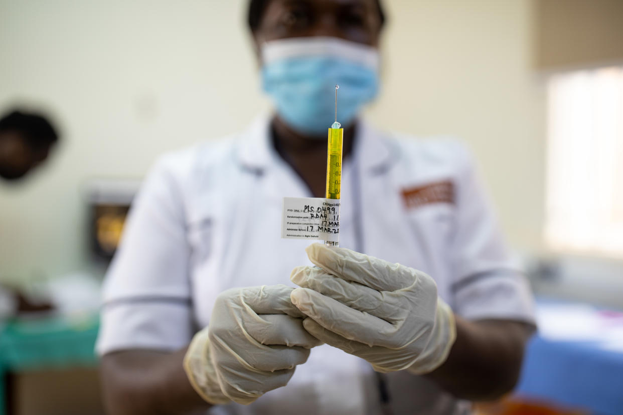 A nurse in rubber gloves and mask prepares a trial dose of PrEPVacc.