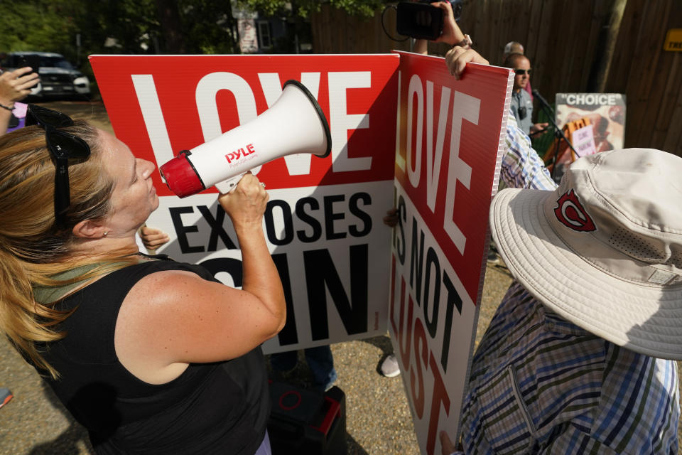 Kim Gibson, co-director of the Jackson Women's Health Organization clinic patient escorts, better known as the Pink House defenders, left, uses a bullhorn to attempt to shout down the speaker system used by anti-abortion activist to speak out to women entering the Jackson Women's Health Organization clinic in Jackson, Miss., Thursday, July 7, 2022. The clinic was the only facility that performed abortions in the state. However, on Tuesday, a chancery judge rejected a request by the clinic to temporarily block a state law banning most abortions. The clinic saw a limited number of patients on Thursday, but not for abortions. (AP Photo/Rogelio V. Solis)