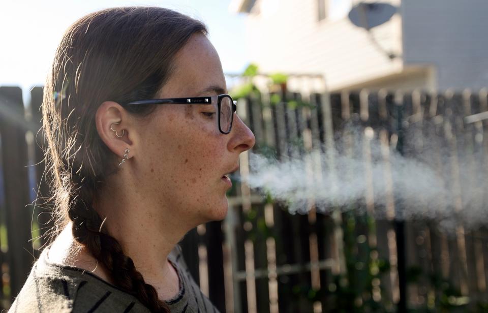 Kerra Davis exhales after using a medical cannabis vape pen outside her home in West Jordan on Friday, July 21, 2023. Davis, a mother of three, uses medical cannabis to treat chronic pain from endometriosis, pelvic congestion syndrome and arthritis. | Kristin Murphy, Deseret News