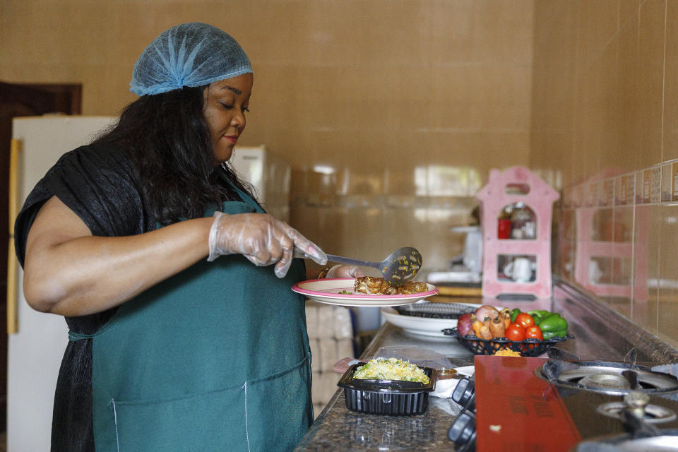 Anita Akpeere, who uses her mobile phone to run her business, prepares food at her restaurant in Accra, Ghana, Tuesday, April 23, 2024. While preparing the food in Ghana's capital a flurry of notifications for restaurant orders lit up apps on her phone. “I don’t think I could work without a phone in my line of business,” she said, as requests came in for her signature dish, a traditional fermented dumpling. (AP Photo/Misper Apawu)