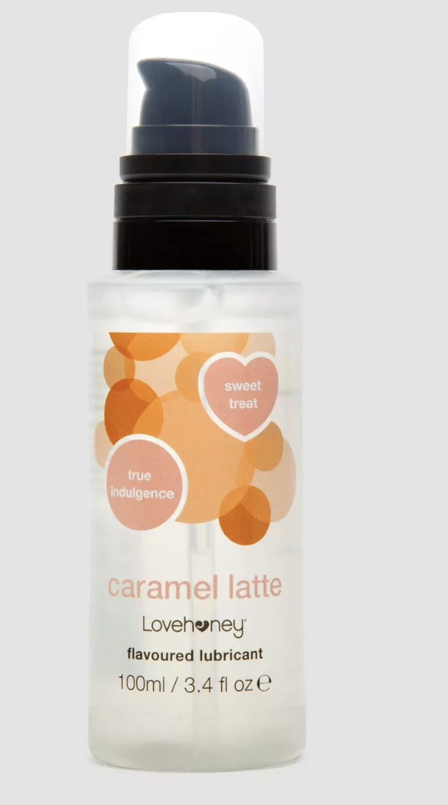 A cream coloured bottle of Lovehoney Caramel Latte Lubricant with caramel and pink toned graphic elements, black writing and a black spray top.